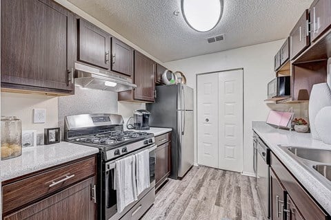 a kitchen with wood cabinets and stainless steel appliances at St. Johns Forest Apartments, Florida, 32277